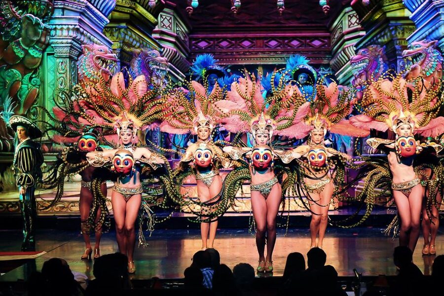 Feathered showgirls mid-number under the lights of a Paris cabaret